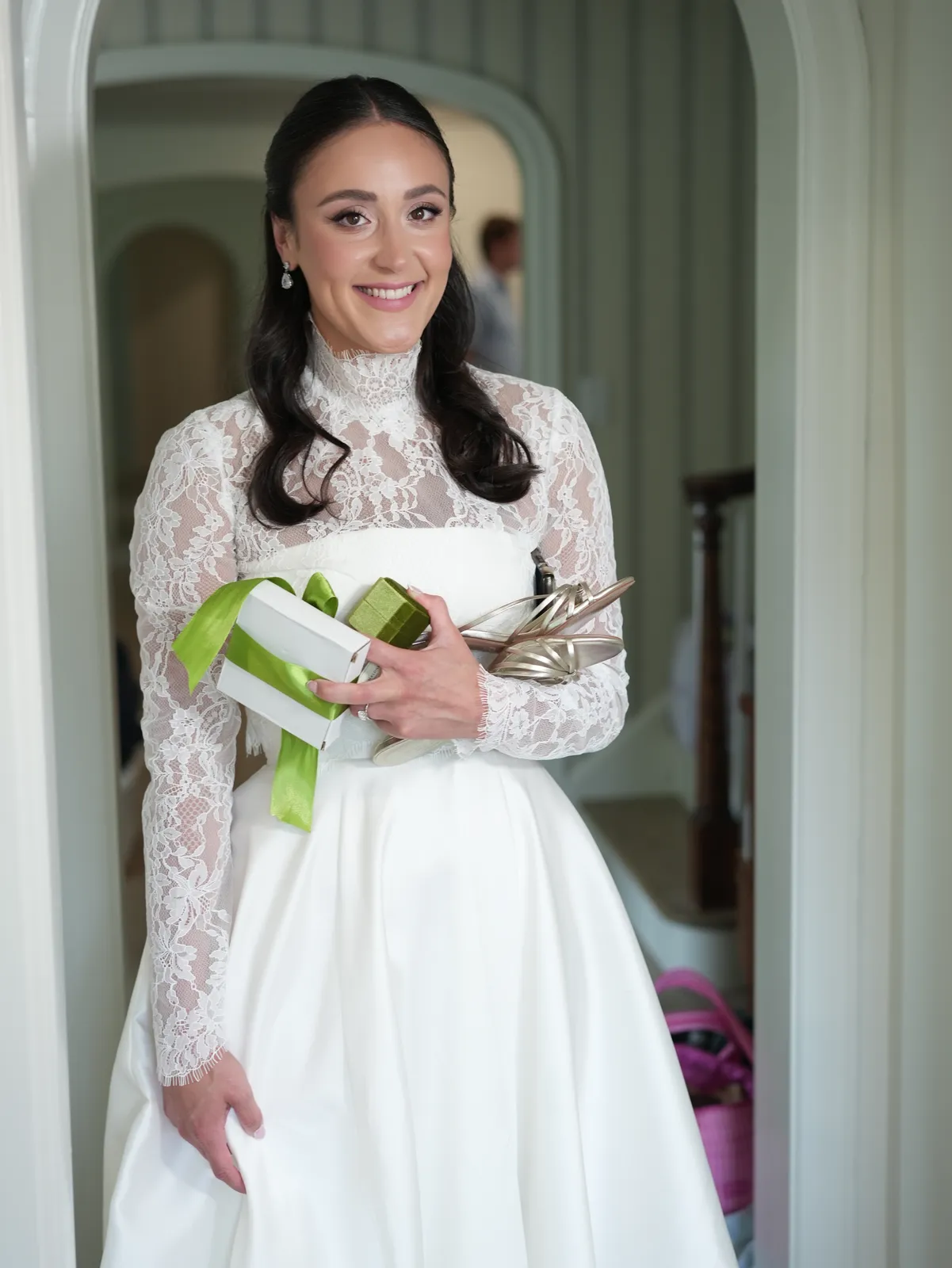 Bride in a lace high-neck gown with soft glam makeup and a sleek half-up style