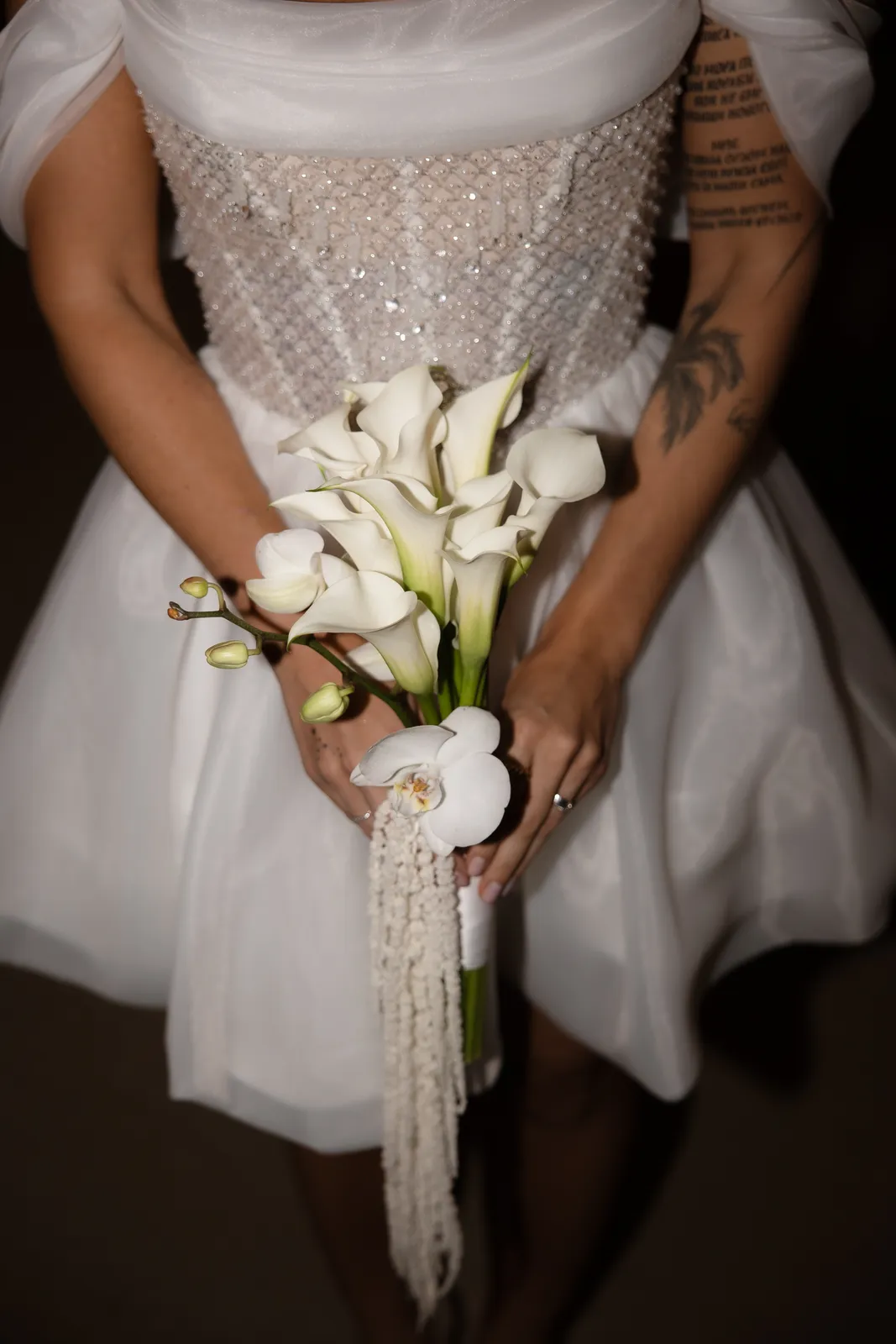 Bride in a beaded short dress holding a calla lily bouquet