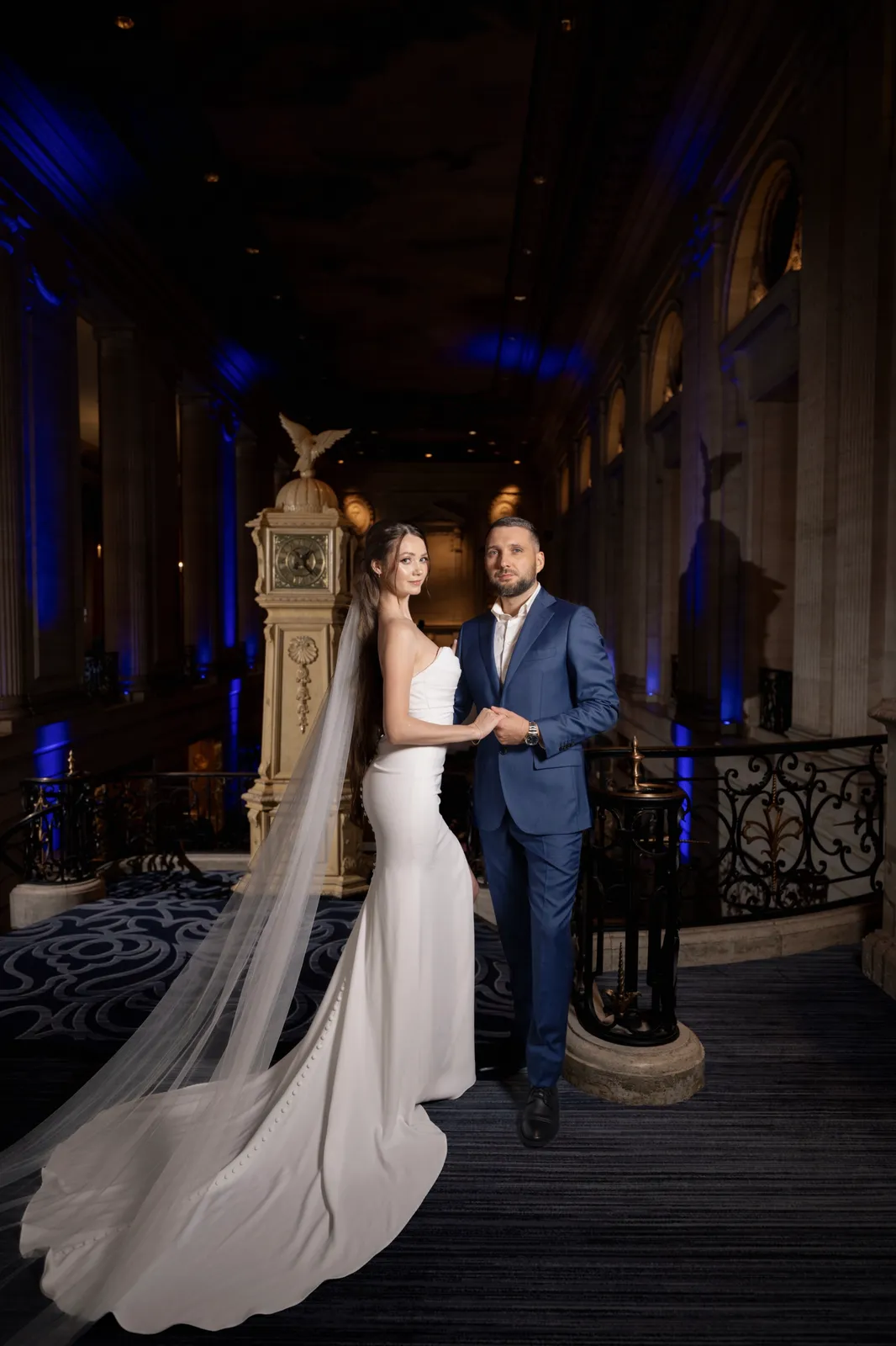 Bride and groom in a grand hotel lobby, bride with a long veil